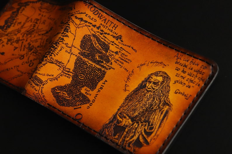 May include: A brown leather wallet with a map of Middle-earth from The Lord of the Rings and a portrait of Gandalf. The text on the wallet reads "All we have to decide is what to do with the time that is given us - Gandalf".