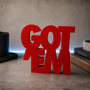 May include: A bright red, three-dimensional decorative sign featuring the text GOT EM in a bold, block-style font. The letters are connected as a single unit, standing upright with a matte finish, designed for display on a flat surface.