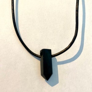 Peut inclure: Un collier avec un pendentif noir en forme de cristal pointu.