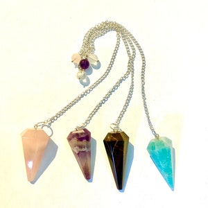 Può includere: Quattro pendolari di cristallo con catene d'argento. I pendolari sono fatti di quarzo rosa, ametista, occhio di tigre e aventurina.