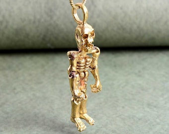 May include: A gold skeleton pendant necklace. The skeleton is detailed and has a realistic look. The necklace is perfect for adding a touch of gothic style to any outfit.