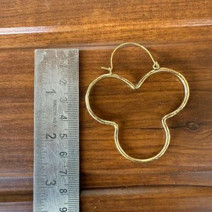 Puede incluir: Pendientes de aro dorados con un diseño único en forma de trébol. Los pendientes miden aproximadamente 5 cm de diámetro.