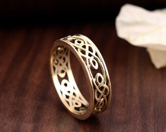 May include: A gold-toned ring featuring a Celtic knot design. The ring is made of metal and has a smooth finish.
