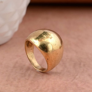 May include: A gold-toned ring with a large, rounded dome-shaped top.