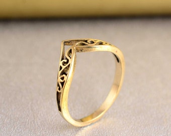 May include: A gold-toned ring with a delicate, intricate design. The ring is shaped like a V and has a filigree pattern.