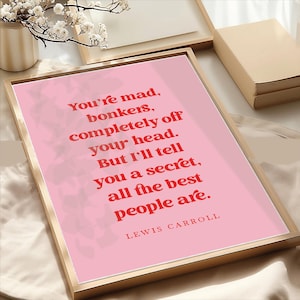 May include: A pink printable wall art print with a quote by Lewis Carroll in red text that reads "You're mad, bonkers, completely off your head. But I'll tell you a secret, all the best people are."