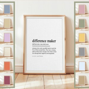 Puede incluir: Una impresión enmarcada en madera con la definición de "difference maker" en texto negro sobre un fondo blanco. La definición incluye la pronunciación y una descripción del término. El marco es de color marrón claro.