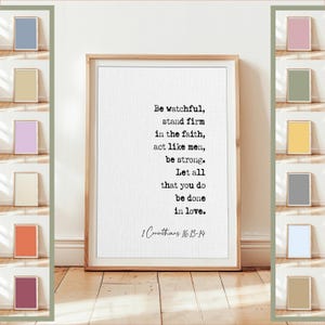 May include: A framed print with the text "Be watchful, stand firm in the faith, act like men, be strong. Let all that you do be done in love. 1 Corinthians 16:13-14." The frame is light brown, and the print is on white paper. Various small framed prints in pastel colors are displayed around the main print.