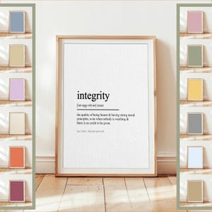 May include: A framed print with the definition of "integrity" in black text on a white background. The definition includes the pronunciation and a description of integrity. The frame is a light brown color. There are several small framed prints in various colors on either side.
