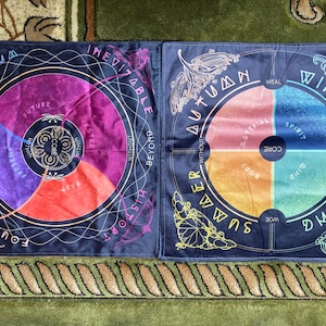 May include: Two circular mandala designs on black fabric with a blue, purple, red, orange, yellow, and green colour scheme. The designs are labelled with the words "Winter", "Spring", "Summer", "Autumn", "Foundation", "History", "Inevitably", "Momentum", "Beyond", "Without", "Material", "Spirit", "Core", "Body", "Mind", "Woe", "Within", "Weal", "Past", "Present", "Future", "Rise", "Fall", "Bask", "With", "Without", "Beyond", "History", "Cated", "Within", "Core", "Future", "Pas", "Prese", "FoundaΤΙΟΝ", "WOWOW Beyond".