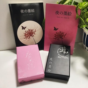 Puede incluir: Dos cajas rosas y una negra con texto japon&eacute;s. Las cajas est&aacute;n decoradas con una flor roja y una mariposa. El texto en las cajas dice "Yoru no Sumi-E", que se traduce como "Pintura de tinta nocturna".