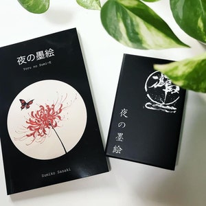 Puede incluir: Dos libros negros con texto blanco en las portadas. El libro de la izquierda tiene una flor roja y una mariposa en la portada. El texto en la portada dice "Yoru no Sumi-e" y "夜の墨絵". El texto en el libro de la derecha dice "夜の墨絵".