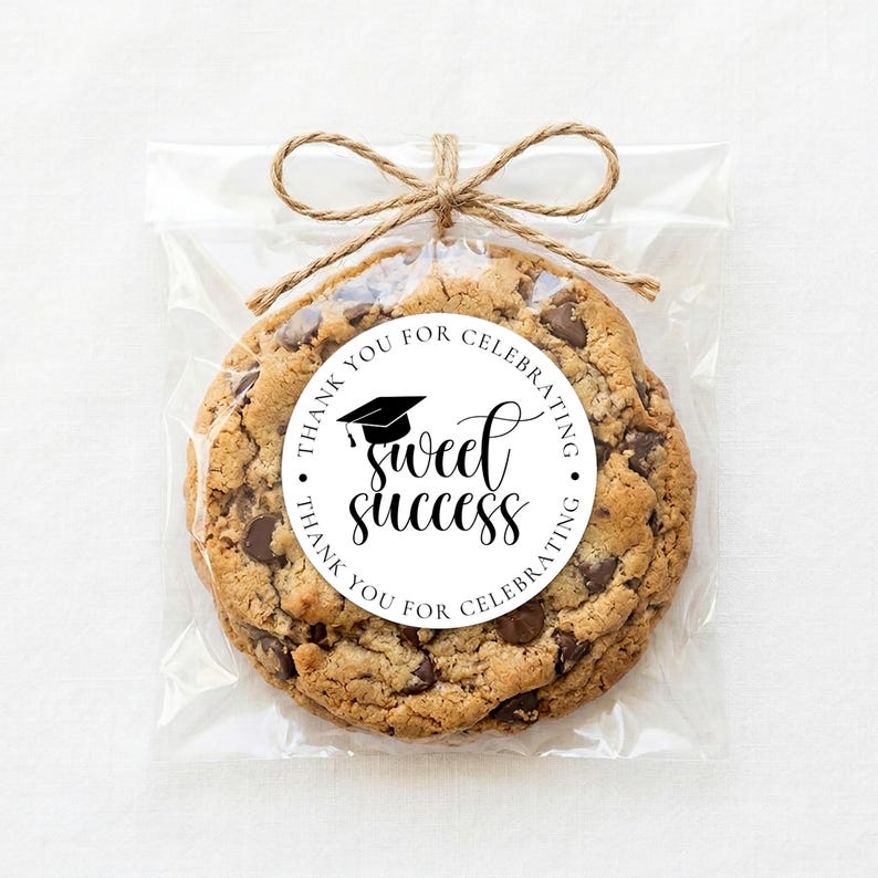 Op de afbeelding: Een chocolate chip cookie in een doorzichtige cellofaan zak, vastgebonden met touw. Een ronde sticker op de cookie leest "Sweet Success" met een afstudeerhoedje en de woorden "Thank you for celebrating."
