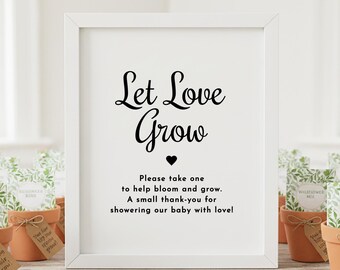 Op de afbeelding: Een wit omkaderd bord met de woorden "Let Love Grow" in elegant zwart schrift. Hieronder staat de tekst "Please take one to help bloom and grow. A small thank-you for showering our baby with love!" Kleine terracotta potten zijn zichtbaar.