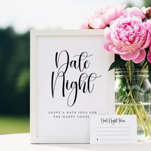 Puede incluir: Un letrero enmarcado en blanco con las palabras "Date Night" en elegante escritura negra. Debajo, el texto dice "Deja una idea de cita para la feliz pareja". Una peque&ntilde;a tarjeta con "Date Night Ideas" y l&iacute;neas est&aacute; al frente. Peon&iacute;as rosas en un tarro de cristal.