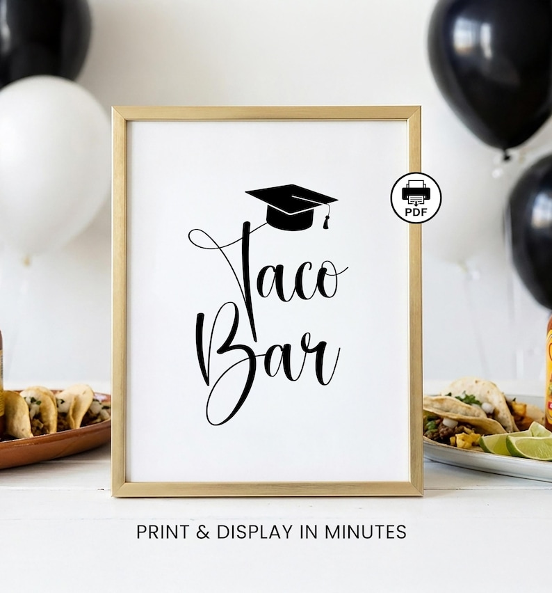 Op de afbeelding: Een ingelijst bord met de woorden "Taco Bar" in elegant zwart schrift, bekroond met een illustratie van een afstudeerpet. Het bord staat in een gouden lijst, met de tekst "PRINT & DISPLAY IN MINUTES" onderaan. Ballonnen zijn op de achtergrond.
