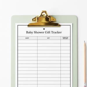 Peut inclure: Un suivi des cadeaux de baby shower sur un presse-papiers vert clair avec un clip doré. Le papier blanc a une bordure noire et le texte "Baby Shower Gift Tracker". Un crayon repose sur le côté droit.