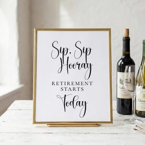 以下が含まれることがあります： 「Sip, Sip Hooray Retirement Starts Today」と黒い筆記体で書かれた、金色のフレーム。白い表面に置かれ、背景にはワインボトルとグラスがあります。