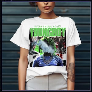 May include: White t-shirt with the text "NEVER BROKE AGAIN" and "YOUNGBOY" in green. The graphic features a person with a blue shirt and a silver chain, with smoke obscuring the face. The design includes other images and text.