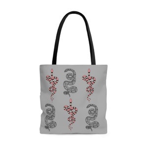 May include: A gray tote bag with a repeating pattern of black and pink snakes. The snakes are in a vertical position and are intertwined.