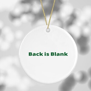 K&ouml;nnte beinhalten: Runder wei&szlig;er Keramik-Anh&auml;nger mit einer gr&uuml;nen Schnur zum Aufh&auml;ngen. Die Vorderseite des Anh&auml;ngers tr&auml;gt den Text "Back is Blank" in gr&uuml;n.