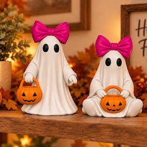 Halloween ghost figurine pair with pink bows and orange pumpkin trick or treat buckets, featuring one standing ghost and one seated ghost.