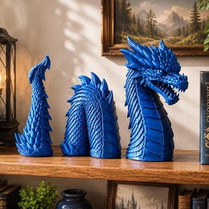 May include: A three-piece blue dragon figurine set consisting of a head, a mid-section, and a tail. Each piece features detailed scales and spikes, with the dragon head showing an open mouth with visible teeth, all arranged in a linear sequence.