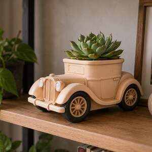 May include: A beige vintage car-shaped planter with a succulent plant. The planter has black wheels and a detailed front grill. The succulent is green and leafy, contrasting with the car's color. The planter sits on a wooden shelf.