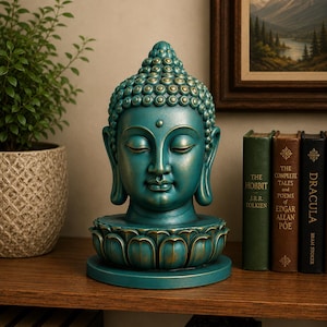 Puede incluir: Una estatua de cabeza de Buda de color verde azulado sobre una base de flor de loto. La escultura presenta un peinado rizado y texturizado, ojos cerrados y lóbulos de las orejas alargados, con sutiles reflejos dorados.
