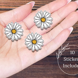 May include: Three white daisy stickers with yellow centers on a hand. The text "10 Stickers Included" is in a circle with a leafy branch design.