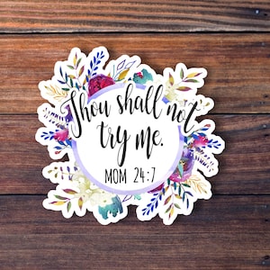 May include: A white sticker with a purple floral wreath around the text "Thou shall not try me. MOM 24:7".