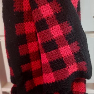 May include: A red and black crocheted blanket with a buffalo check pattern.
