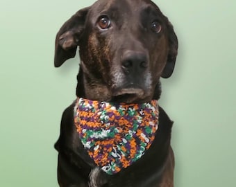 May include: A brown and black dog wearing a green, orange, purple and white crocheted bandana.
