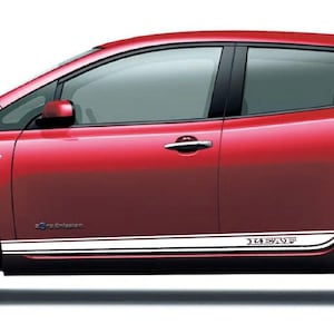 Op de afbeelding: Een rode Nissan Leaf elektrische auto met een witte streep langs de zijkant en de tekst "LEAF" aan de zijkant.