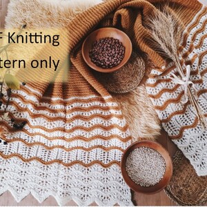May include: A PDF knitting pattern for a white and brown striped blanket with a crocheted border. The blanket is laid out on a faux fur rug with a bowl of coffee beans and a bowl of white seeds.