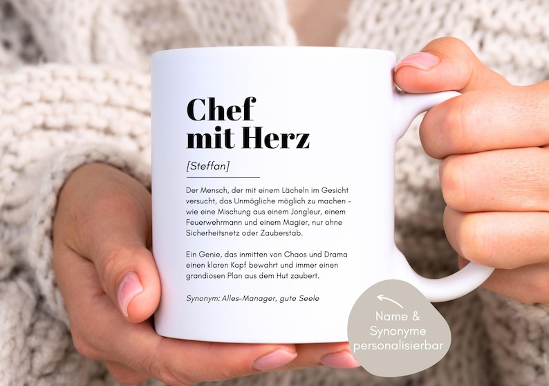 May include: White ceramic mug with a black design that reads "Chef mit Herz [Steffan]" and a definition of the term in German. The mug has a black handle and a black rim. The text on the mug is "Der Mensch, der mit einem L&auml;cheln im Gesicht versucht, das Unm&ouml;gliche m&ouml;glich zu machen - wie eine Mischung aus einem Jongleur, einem Feuerwehrmann und einem Magier, nur ohne Sicherheitsnetz oder Zauberstab. Ein Genie, das inmitten von Chaos und Drama einen klaren Kopf bewahrt und immer einen grandiosen Plan aus dem Hut zaubert. Synonym: Alles-Manager, gute Seele". The text "Name & Synonyme personalisierbar" is also on the mug.