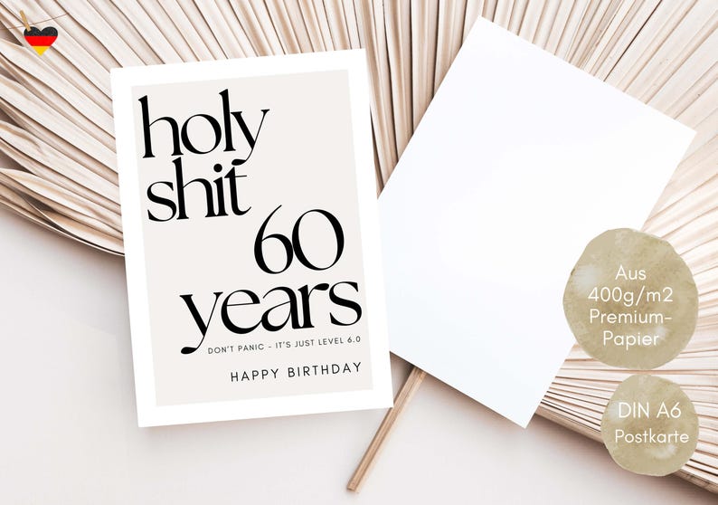 May include: A birthday card with the text "holy shit 60 years" in black font. The card also includes the phrases "DON'T PANIC - IT'S JUST LEVEL 6.0" and "HAPPY BIRTHDAY". A blank card and two circular labels are also visible.