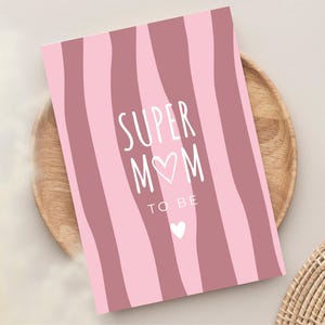 Könnte beinhalten: Eine rechteckige Grußkarte mit einem vertikalen Wellenstreifenmuster in abwechselnden Farbtönen von Hellrosa und Altrosa. Der Text "SUPER M♥M TO BE" ist in Weiß gedruckt, mit einem kleinen weißen Herzsymbol unter dem Text.