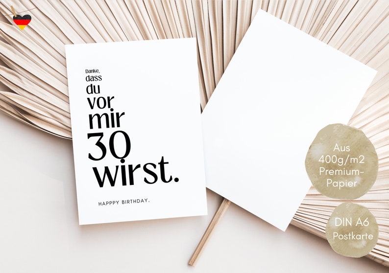 May include: A white card with black text that reads "Danke, dass du vor mir 30 wirst. HAPPY BIRTHDAY." The card is on a light brown background.
