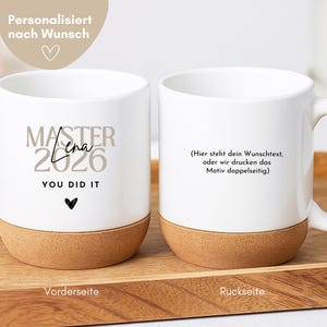May include: Two white ceramic mugs with cork bases. The left mug features the text "MASTER 2026", the name "Lena" in script, "YOU DID IT", and a small heart. The right mug displays German text regarding custom printing options on the back side.