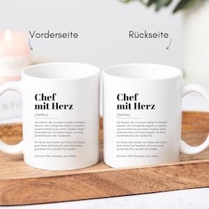 May include: Two white ceramic mugs with black text that reads "Chef mit Herz [Steffan]"  The text defines the word "Chef mit Herz" as "The person who tries their best to make the impossible possible, a leader who inspires, a person who always has a plan and never gives up."