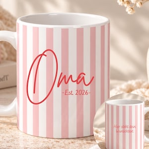 May include: A white ceramic mug featuring vertical light pink stripes. The front displays the red text "Oma" in a large script font, followed by "-Est. 2026-" in a smaller font. A smaller inset shows the same mug with the text "Hier steht dein Wunschtext".