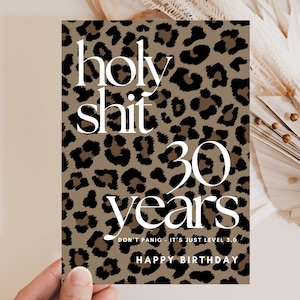 May include: A rectangular birthday greeting card featuring a brown and black leopard print pattern. The text reads holy shit 30 years, followed by the smaller text DON'T PANIC - IT'S JUST LEVEL 3.0 and the words HAPPY BIRTHDAY at the bottom.