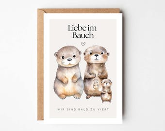 Könnte beinhalten: Eine Karte mit einer Aquarell-Illustration von zwei Ottern und einem kleineren Otter im Bauch eines der Otter. Der Text auf der Karte lautet "Liebe im Bauch" und "Wir sind bald zu viert".