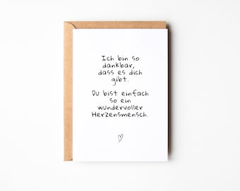 May include: A white card with black handwritten text that reads "Ich bin so dankbar, dass es dich gibt. Du bist einfach so ein wundervoller Herzensmensch." with a small heart symbol at the bottom.