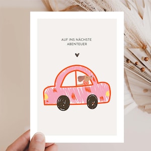May include: A greeting card featuring a pink car illustration with the German text "AUF INS NÄCHSTE ABENTEUER". The car has black wheels and a dog is driving. A small black heart is above the car.