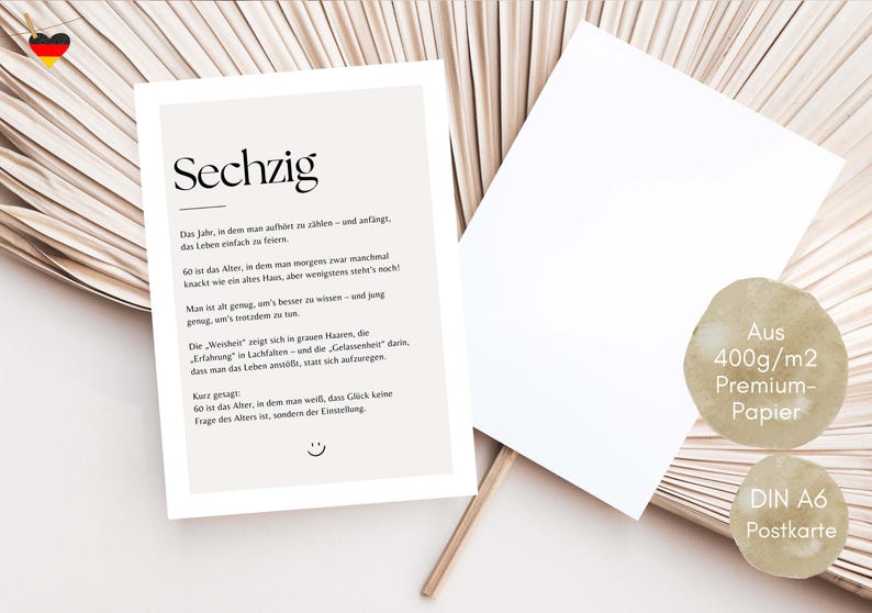 May include: A beige postcard with the word "Sechzig" printed in black. The postcard has text in German and a small smiley face at the bottom. A blank white card is next to it.