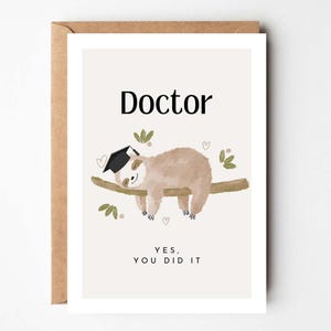 Pode incluir: Cartão de formatura com uma ilustração de bicho-preguiça. O cartão diz "Doctor" no topo, com uma preguiça usando um chapéu de formatura descansando em um galho. Abaixo da preguiça, o cartão diz "Yes, You Did It". O cartão está em um envelope marrom.