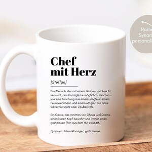 May include: White ceramic mug with black text that reads "Chef mit Herz [Steffan]" and a definition of the term in German. The text says "The person who tries to make the impossible possible with a smile on their face - like a mix of a juggler, a firefighter and a magician, only without a safety net or magic wand. A genius who keeps a clear head in the midst of chaos and drama and always conjures up a grand plan out of their hat. Synonym: All-Manager, good soul."