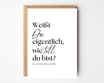 May include: A white card with black text that reads "Weist du eigentlich, wie toll du bist?"  The text is in a cursive font. Below the text is a smaller line of text that reads "Du wunderschöne Seele".